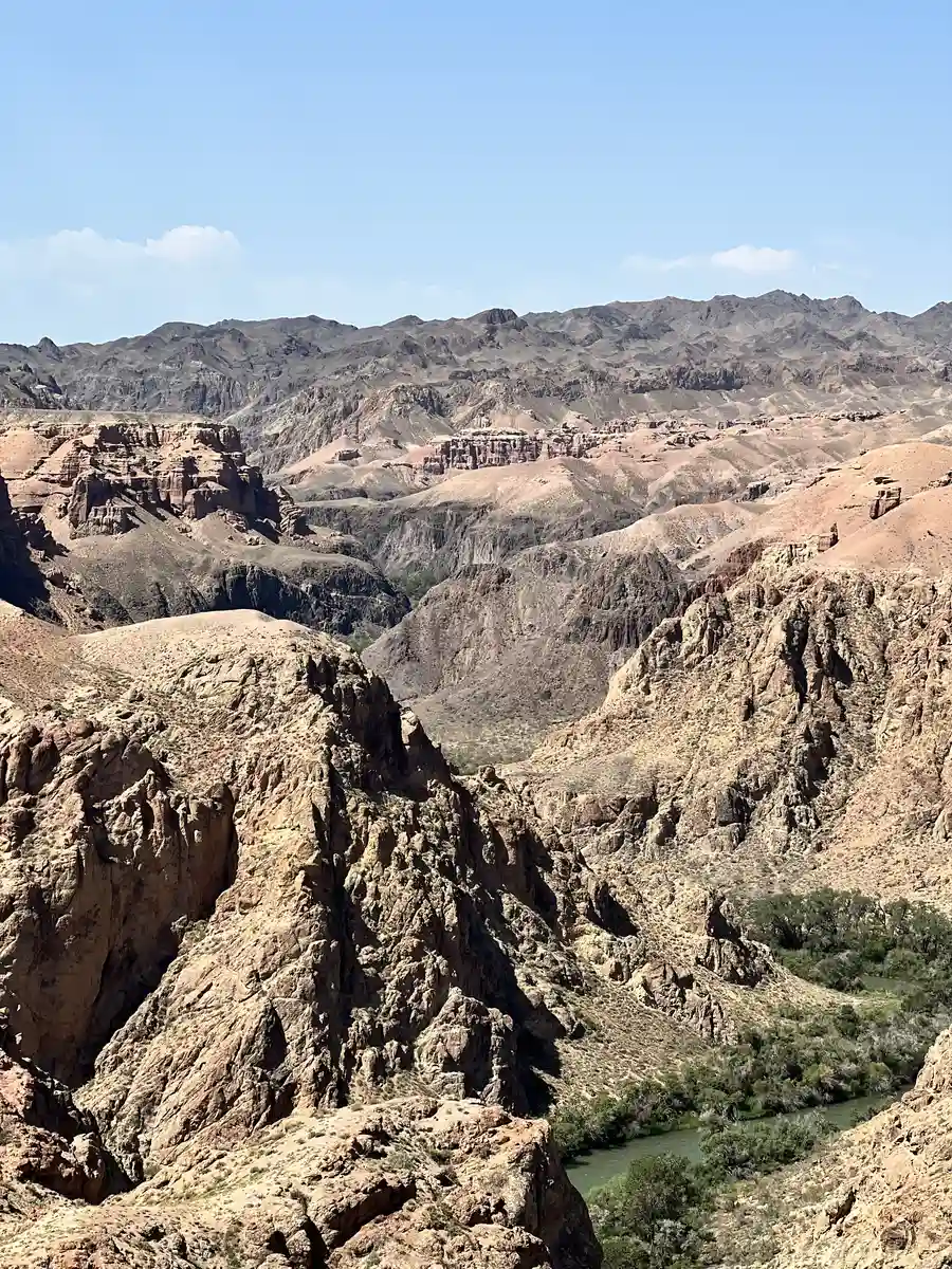 Wide view over the jagged rock formations of Charyn Canyon with the river visible below